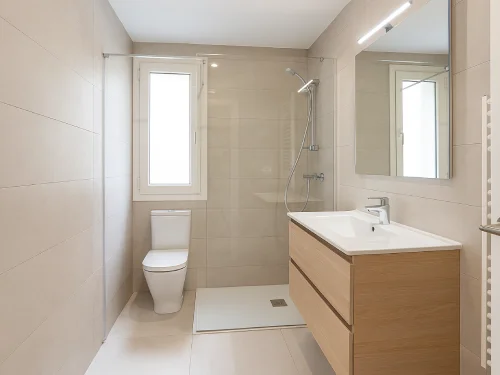 Baño renovado en Mataró con ducha amplia, mampara de cristal y azulejos beige