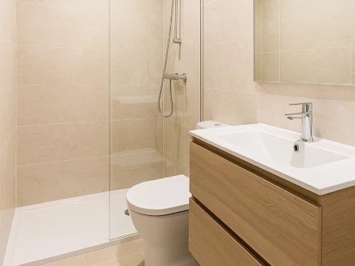 Baño moderno reformado con plato de ducha en Sant Cugat del Vallès Baño reformado en Sant Cugat del Vallès con plato de ducha, alicatado beige, mueble de madera y grifería cromada